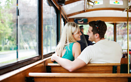 A couple sitting on a trolley as part of the Wine Trolley Signature Trio Package.