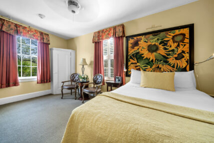 A queen-sized bed with a sunflower painting in the Renoir Room at The Charles Hotel in Niagara-on-the-Lake.