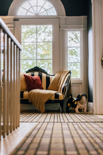A distant view of a striped black and white couch with a bulldog statue beside it at The Charles Hotel in Niagara-on-the-Lake.