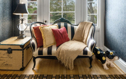 Black and white striped couch with a blanket on top of it, with a bulldog statue beside it at The Charles Hotel in Niagara-on-the-Lake.