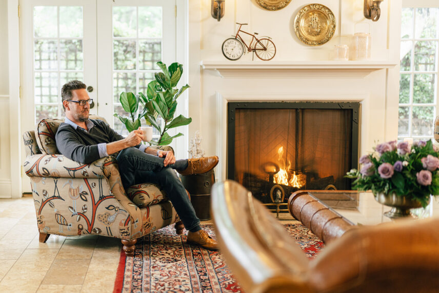 A man sitting on a chair in a living room drinking coffee at Harbour House Hotel in Niagara-on-the-Lake.