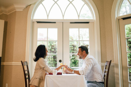 A couple holding hands at a dining table at Harbour House Hotel in Niagara-on-the-Lake.