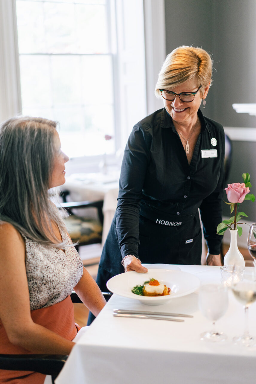 A woman being served at a dining table at one of Niagara's Finest Hotels.