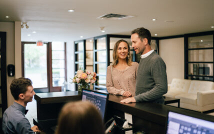 Two people at a hotel check-in desk at Niagara's Finest Hotels.