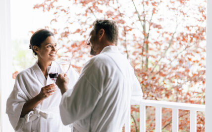 A couple wearing robes and drinking wine at Niagara's Finest Hotels in Niagara-on-the-Lake at an Exclusive getaway package.