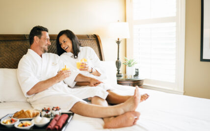 A couple in bed having drinks as part of the Niagara's Finest Romance package.