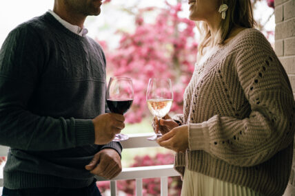 A couple holding wine on a porch at the Shaw Club in Niagara-on-the-Lake.