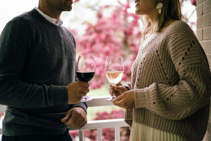 A couple holding wine on a porch at the Shaw Club in Niagara-on-the-Lake.