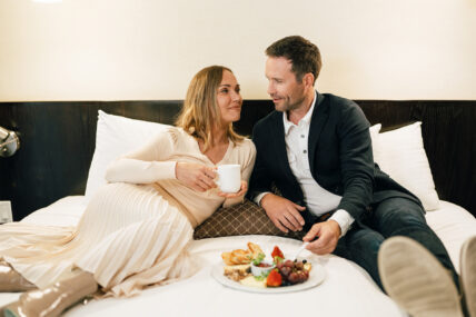 A couple eating food on a bed at the Shaw Club in Niagara-on-the-Lake.